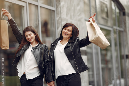 Women on a gray building background. Ladies with shopping bags. Mother with daughter.