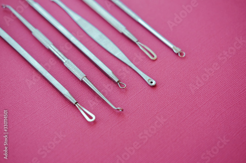 Tools for removing acne. Tools of the cosmetologist for problem skin on pink paper background.