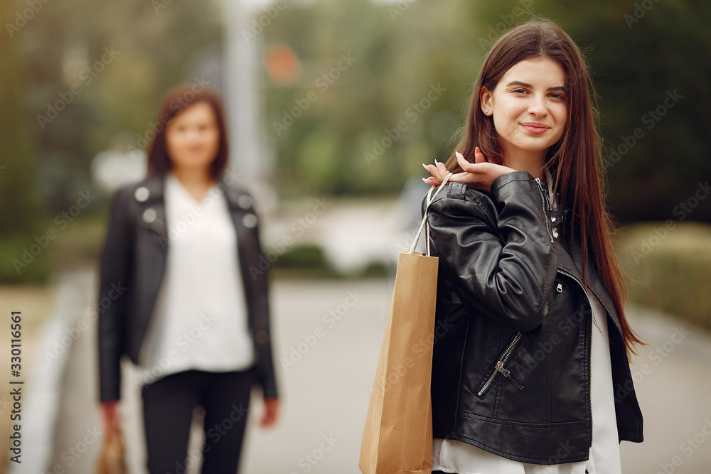 Fototapeta premium Beautiful girls in a summer city. Ladies with shopping bags. Mother with daughter.