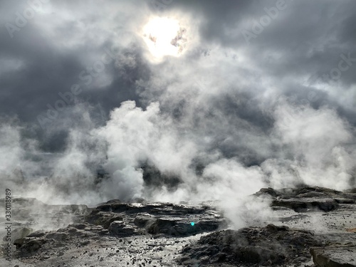 volcanic hotspring with steam under the sun