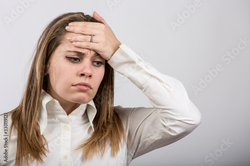 donna con sintomi dell'influenza : mette la mano sulla testa per capire se ha la febbre  , isolata su sfondo bianco  photo