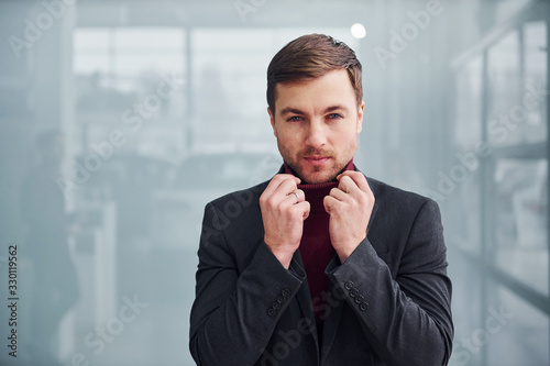 Young business man in luxury suit and formal clothes is indoors in the office