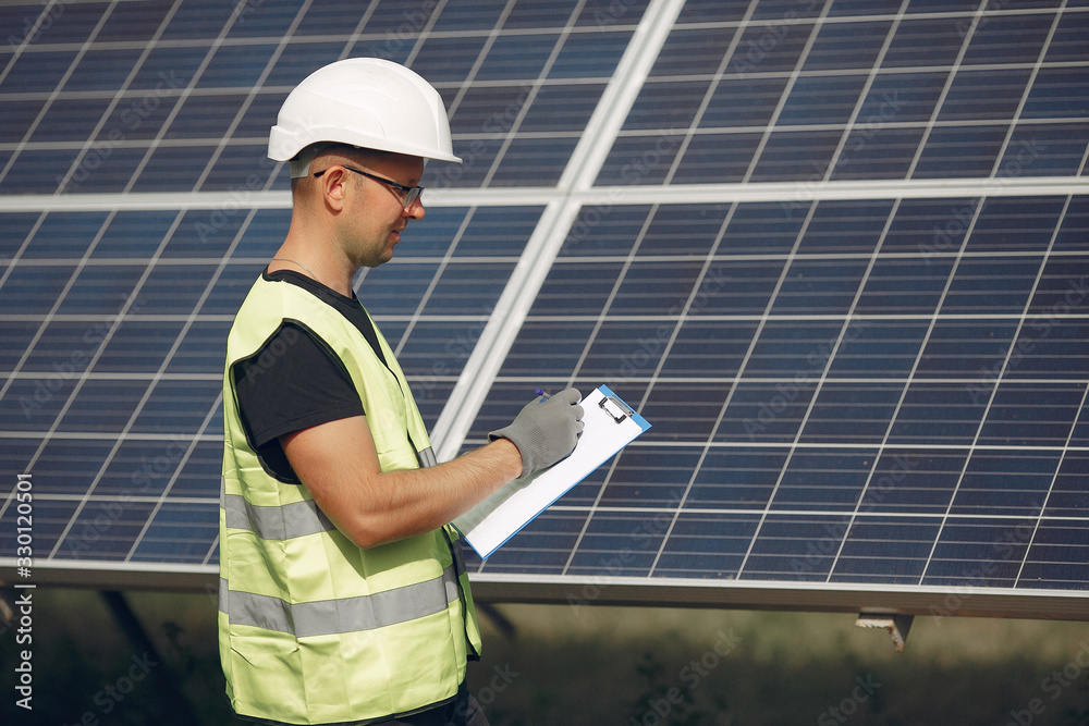 Engineer in a white helmet. Man near solar panel. Worker with a folder. Engineer in a white helmet. Man near solar panel. Worker with a folder.