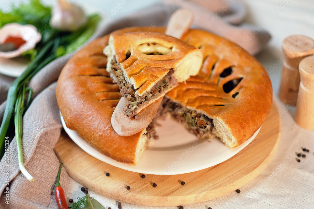 Round closed homemade baked pie with meat and cabbage. Round closed homemade baked pie with meat and cabbage.