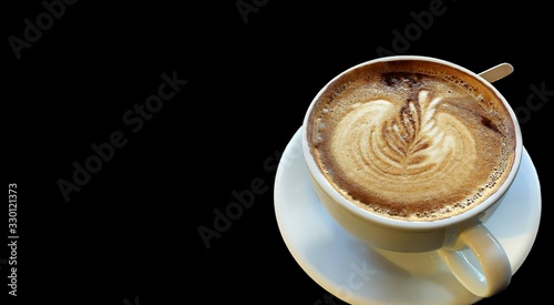 Cappuccino coffee in a white cup at black background with copy space