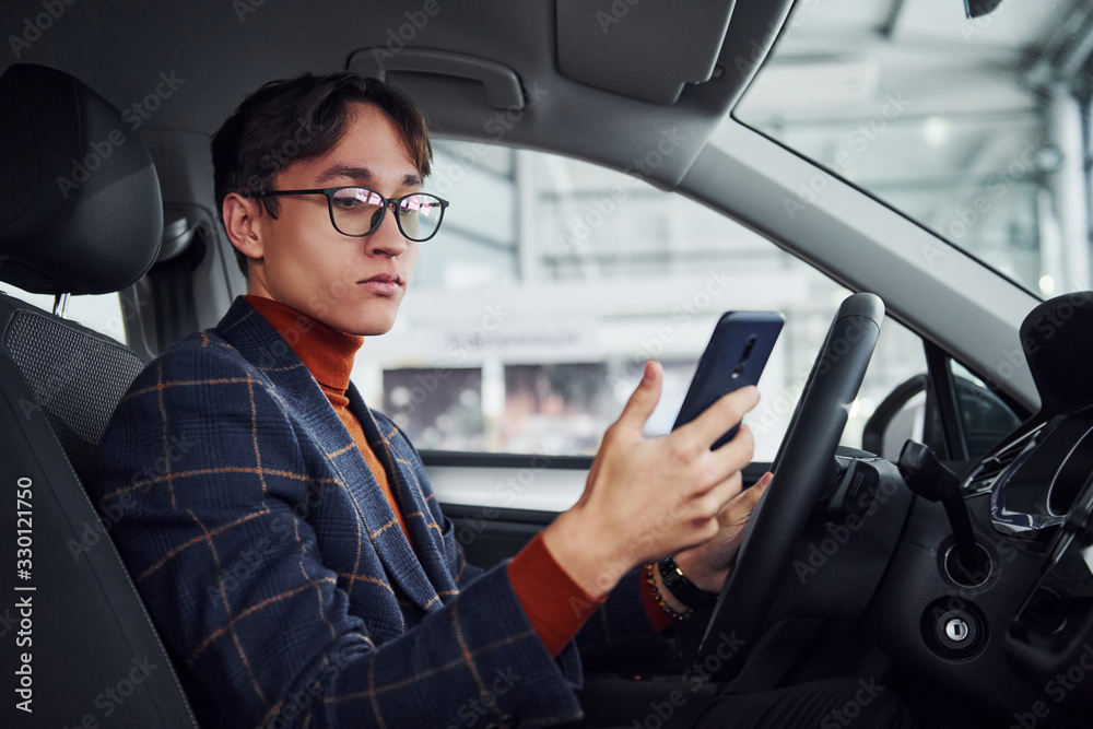 Man in eyewear and formal clothes sitting inside of modern car