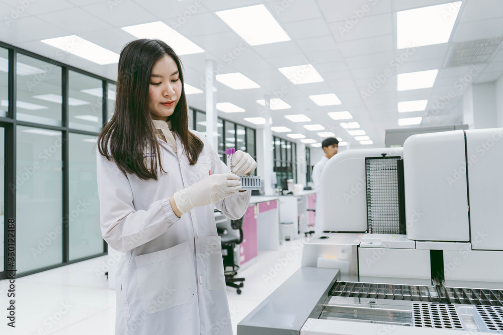 young female scientist working with automation blood analyzer in medical laboratory young female scientist working with automation blood analyzer in medical laboratory