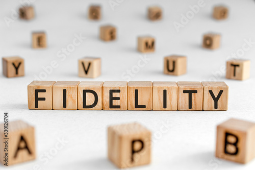 Fidelity - word from wooden blocks with letters, loyalty allegiance fidelity concept, random letters around white background photo