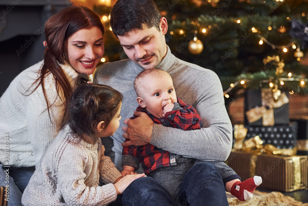 Beautiful caucasian couple celebrating christmas indoors with their little son and daughter