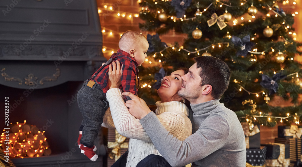 Obraz premium Beautiful caucasian couple celebrating christmas indoors with their little son