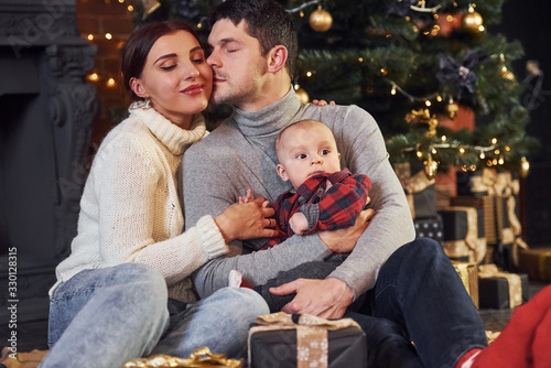 Beautiful caucasian couple celebrating christmas indoors with their little son