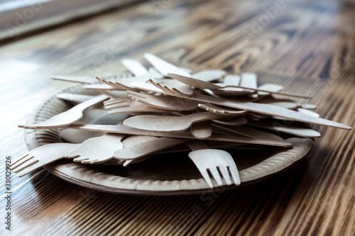 Disposable cutlery, dishes made from natural materials, wooden spoon, fork, knife on a wooden background, environmentally friendly. Place for text. mock up