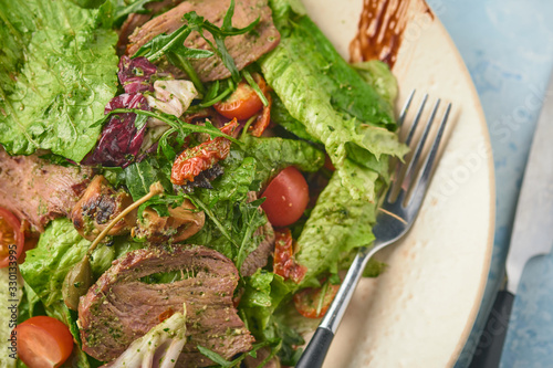 Warm salad with beef, cherry tomatoes and sun-dried tomatoes. Healthy food photo