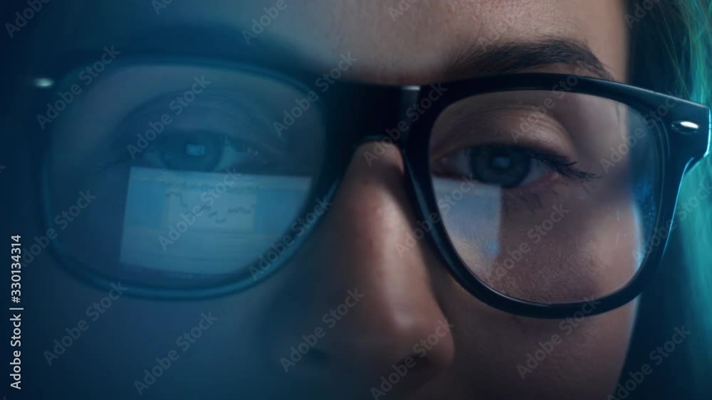 Close up of tired woman working at night on laptop, girl in eye glasses with reflections overworking busy, using computer in dark office Close up of tired woman working at night on laptop, girl in eye glasses with reflections overworking busy, using computer in dark office