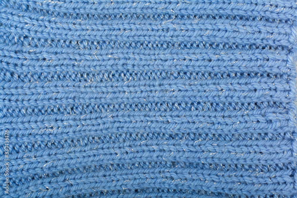 Sweater or scarf fabric texture large knitting. Knitted jersey background with a relief pattern. Braids in knitting . Wool hand- machine, handmade, blue. Sweater or scarf fabric texture large knitting. Knitted jersey background with a relief pattern. Braids in knitting . Wool hand- machine, handmade, blue.