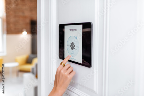 Controlling home ventilation or conditioning with a digital touch screen panel. Concept of wireless ventilation control and smart home photo