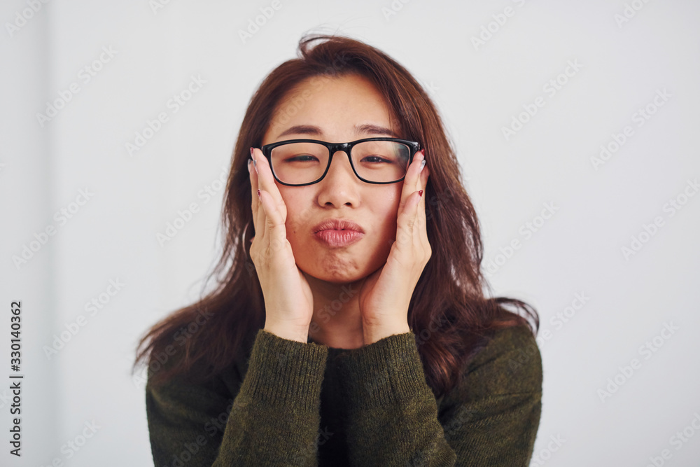 Portrait of happy asian young girl in eyewear that standing indoors in the studio against white background Portrait of happy asian young girl in eyewear that standing indoors in the studio against white background