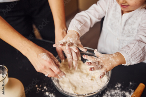 Close up view of mother with her little daughter that preparing food on kitchen and have fun