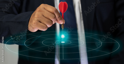 The hand of a male businessman holding a dart and aimed at the graphic target, Targeting the business concept.