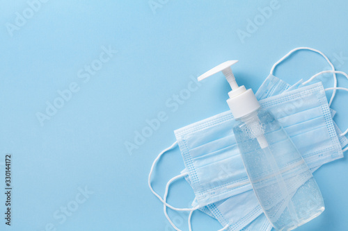 Sanitizer gel or antibacterial soap and face mask for coronavirus preventive measure, top view photo