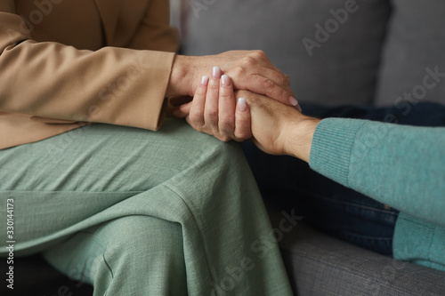 Close-up of woman sitting on sofa and holding hand of the man she care about him