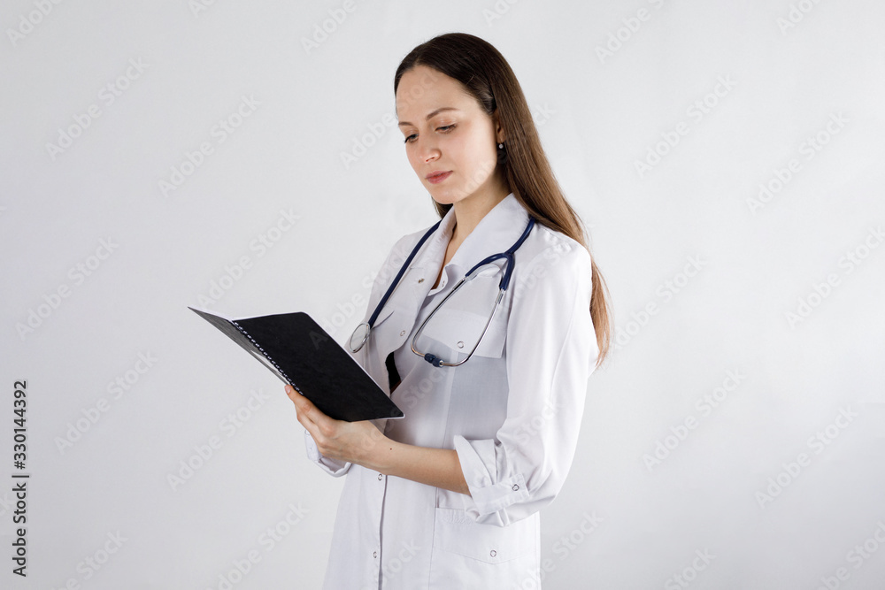 girl doctor looks in a notebook, on a light background girl doctor looks in a notebook, on a light background