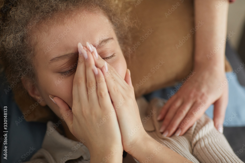 Young sad woman lying and crying while her friend consoling her
