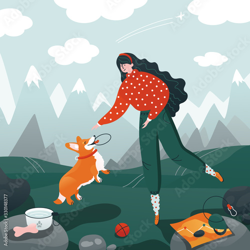 Pet travel. Woman playing with funny corgi on nature. Mountain's landscape.