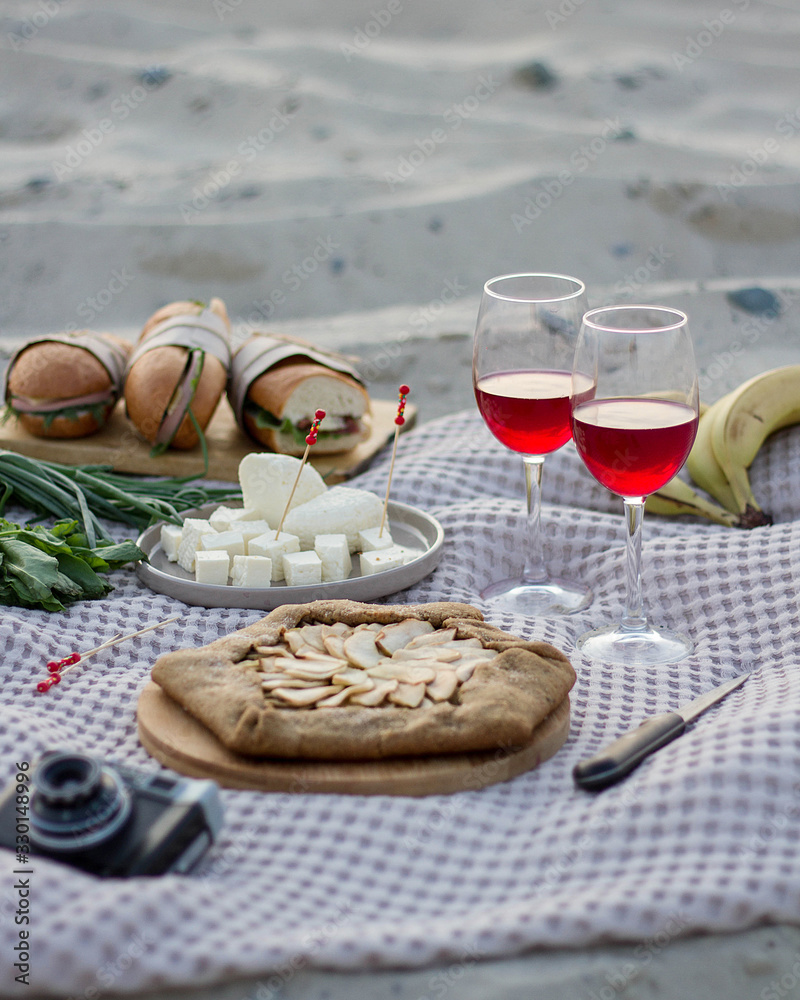 Picnic on the sandy beach with Apple pie and red wine in glasses.