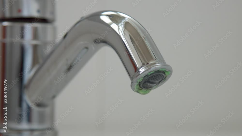 Closeup of a flowing faucet with water drops falling. Moderate consumption concept