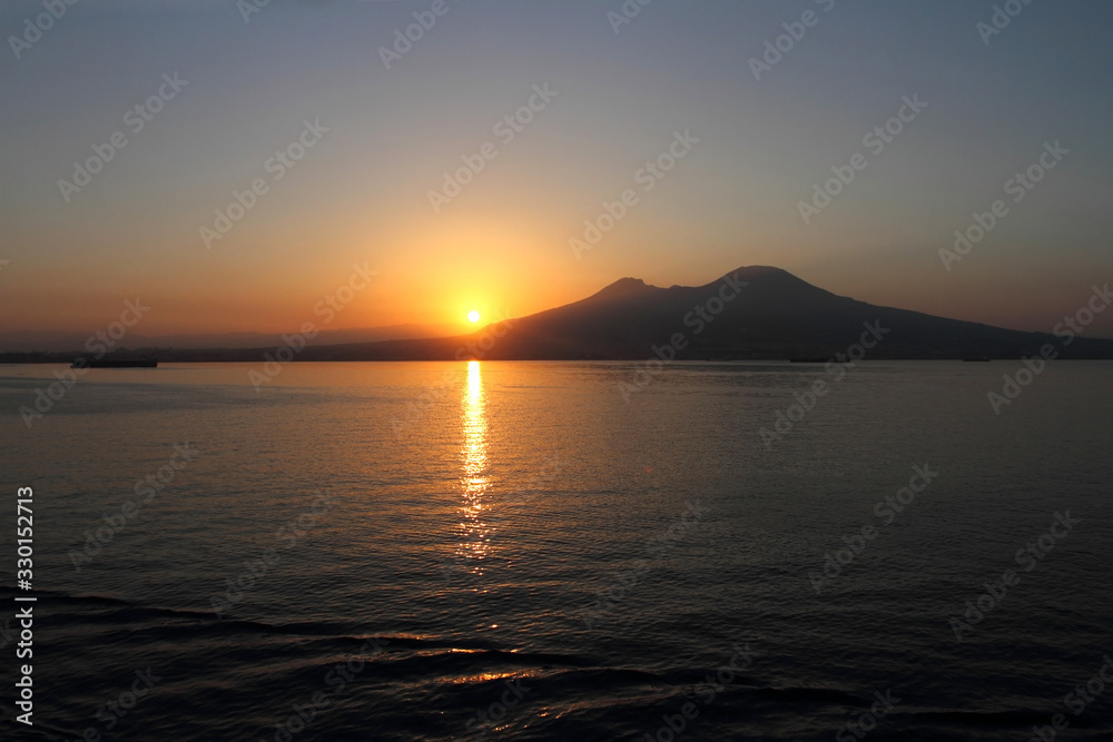 Napoli all'alba, il sole che sorge dietro il Vesuvio visto dal mare