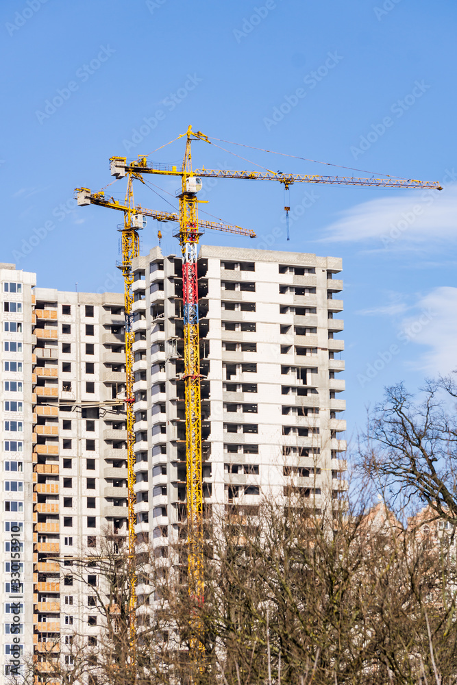 Construction of a high-rise building with a crane. Building construction using formwork. The construction crane and the building against the blue sky