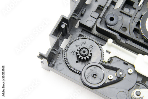Disassembled optical CD-ROM drive in black. Opened CD reader. Drive, laser, motor, gears and other mechanisms. White isolated background.