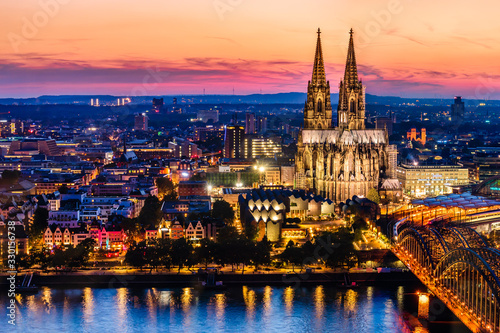 Beautiful night landscape of the gothic Cologne cathedral, Hohenzollern Bridge and the River Rhine at sunset and blue hour in Cologne, Germany