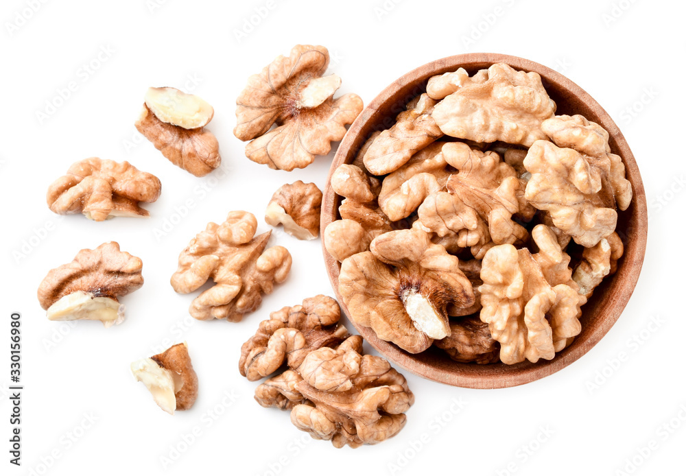 Walnut peeled in a wooden plate and scattered on a white background. The view fromtop. Walnut peeled in a wooden plate and scattered on a white background. The view fromtop.