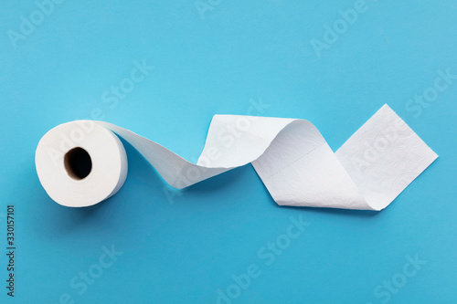 A single roll of toilet paper unrolled on a blue background photo
