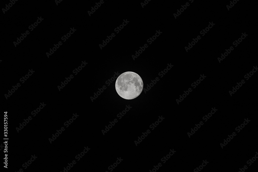 A very detailed photo of a bright full moon in the night sky on a full moon. A full supermoon in a black sky in the dead of night. The background of the full moon. A very detailed photo of a bright full moon in the night sky on a full moon. A full supermoon in a black sky in the dead of night. The background of the full moon.