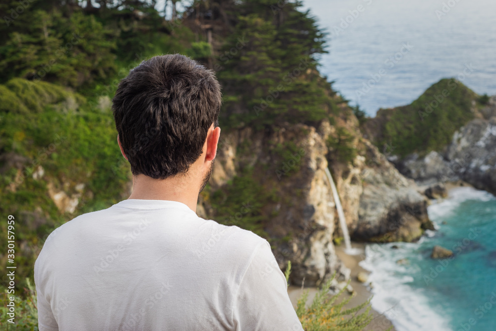 A man looks down at McWay falls in Big Sur, California A man looks down at McWay falls in Big Sur, California