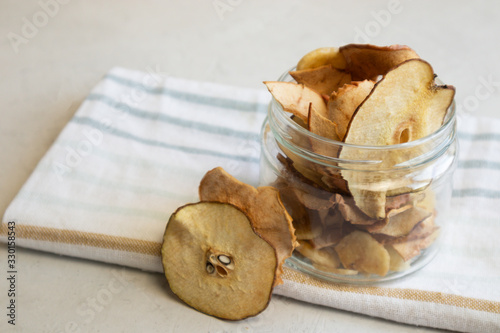 Close-up of a jar with apple fruit chips on a striped napkin. photo