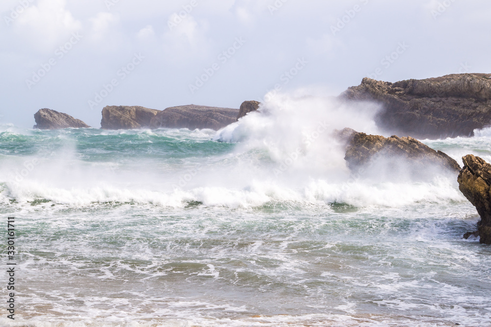 Very large wave breaking against the cliffs in winter with drama