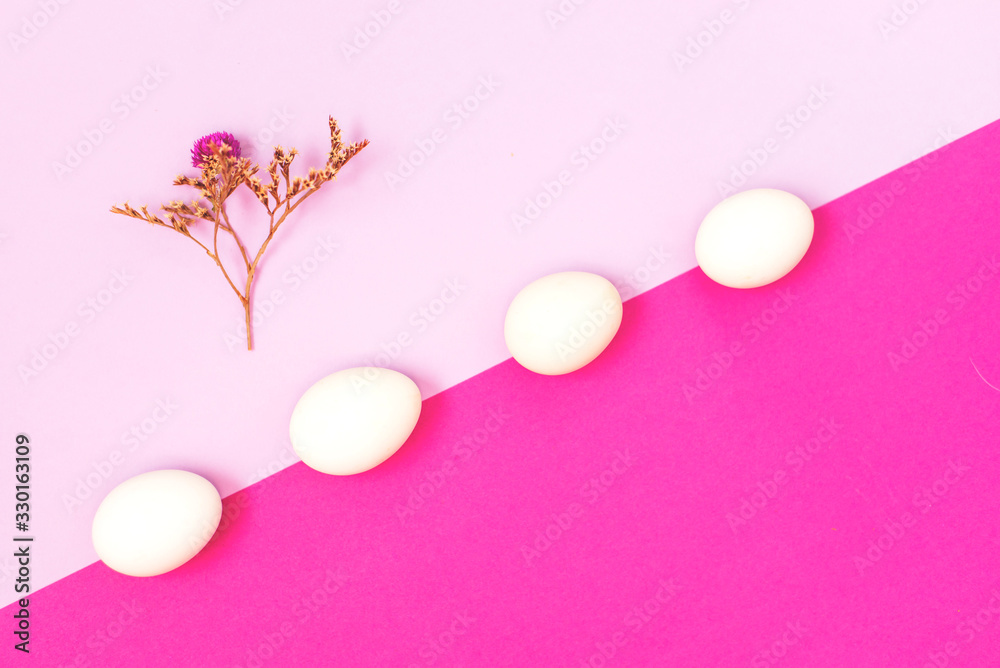 White easter egg on a lilac and rose background with dry flowers, flat lay.