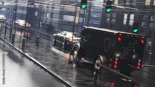 A heavy, black armoured truck going through the city during rainy weather. 4KHD photo