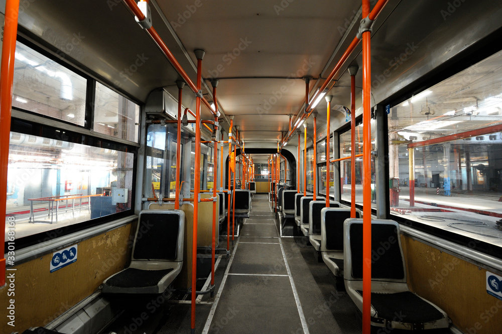 Interior of the modern trolleybus, blue seats, orange handrails, windows