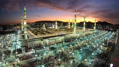 Time lapse of pilgrims performing prayer in illuminated Prophet's Mosque in Medina at sunset, Islam religion and stunning architecture in Saudi Arabia photo