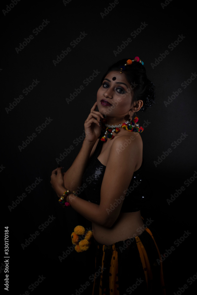 Fashion portrait of Indian brunette woman in Indian traditional tribal dress and handmade ornaments in dark copy space studio background.Indian lifestyle and fashion photography. Fashion portrait of Indian brunette woman in Indian traditional tribal dress and handmade ornaments in dark copy space studio background.Indian lifestyle and fashion photography.
