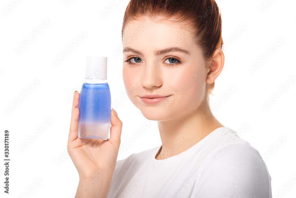 beautiful smiling teen girl with clean skin holding bottle with blue makeup remover, isolated on white beautiful smiling teen girl with clean skin holding bottle with blue makeup remover, isolated on white