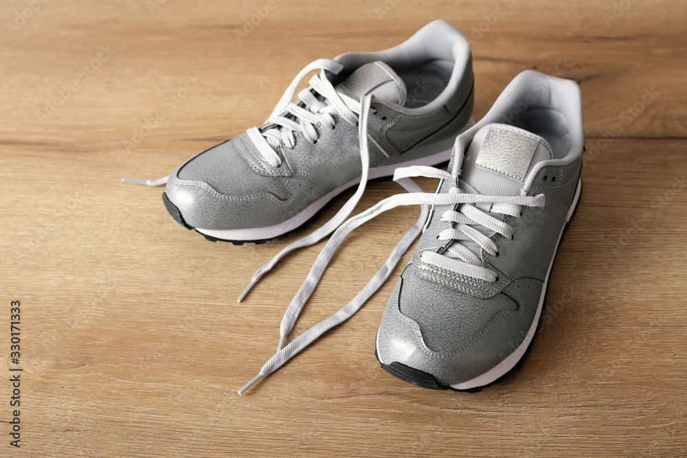 New gray sneakers on a light wooden background New gray sneakers on a light wooden background