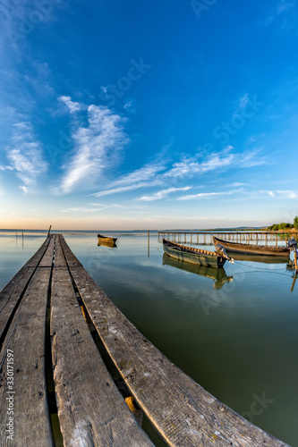 Fototapeta Naklejka Na Ścianę i Meble -  Beautiful morning landscape with boats on the lake anchored to the pier and wood bridges at sunrise, Razelm Razim Lake, Sarichioi, Romania