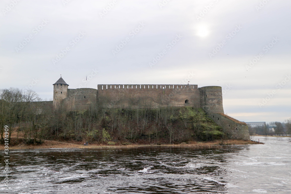 Spring view to Ivangorod fortress on the river Narva with little cold sun in the sky