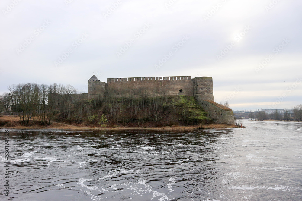 Spring view to Ivangorod fortress on the river Narva with little cold sun in the sky